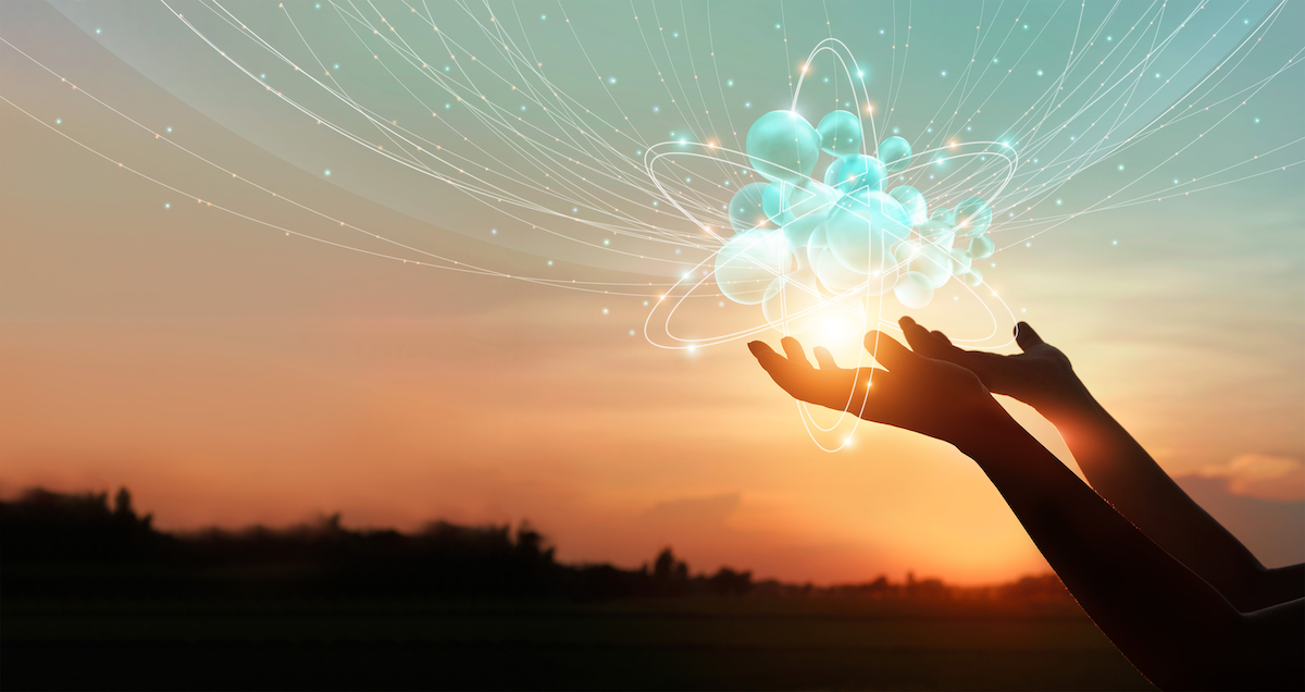 A photo of a pair of hands holding global network connection icons against sunset sky to illustrate collaboration on open networking